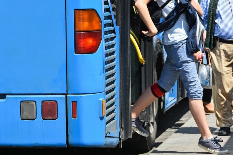 Passengers exiting the back door of a blue public bus.